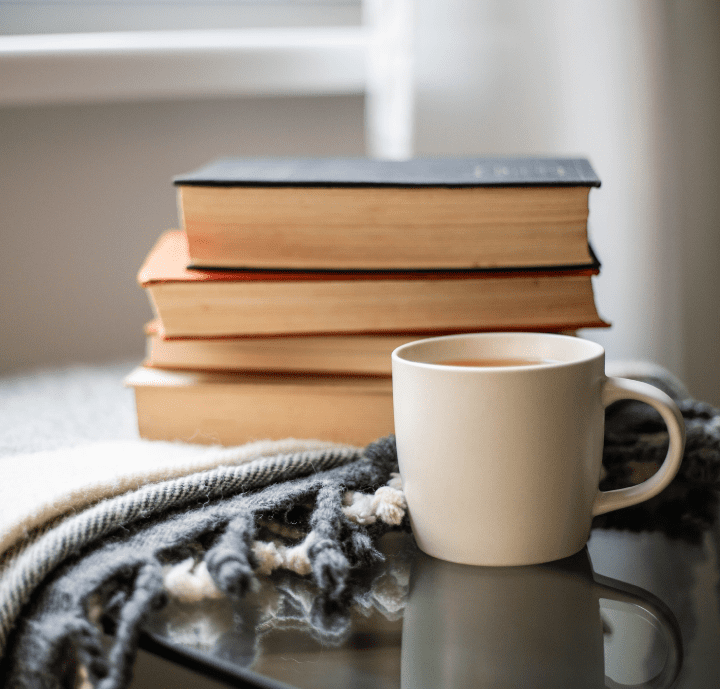 Books and coffee on a cozy blanket.
